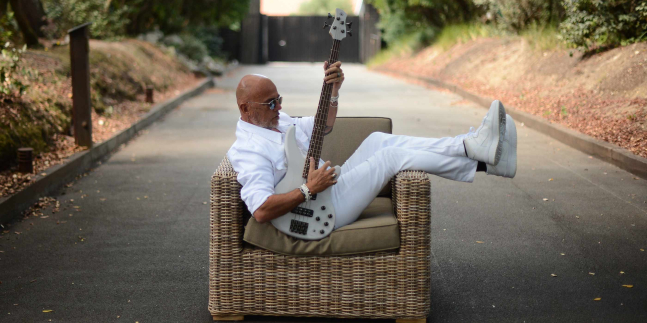 Pascal Obispo dans un fauteuil dans on jardin avec une guitare
